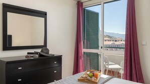 A bedroom with a bed, a dresser, a mirror, and a window with curtains. - Golden Star AU – Elegance in Funchal (Funchal)
