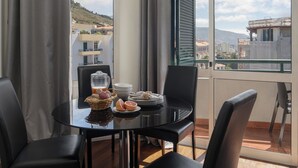 A balcony with a table set for breakfast, including a fruit basket, plates, and a pitcher. - Golden Star AU – Elegance in Funchal (Funchal)