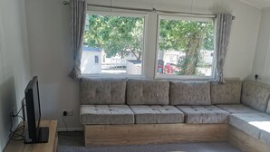Una sala de estar moderna con un sofá modular, una mesa de centro de madera y un televisor.