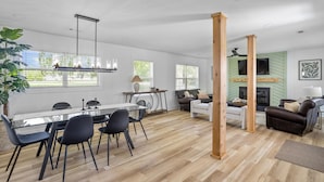 A spacious living area with a dining table, chairs, a sofa, and a fireplace. - Private home near Greensboro GSO Airport 20% off in checkout limited time (Kernersville)