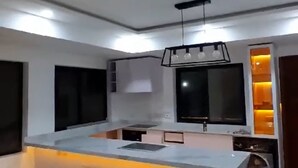 A modern kitchen with a central island, built-in appliances, and pendant lighting.