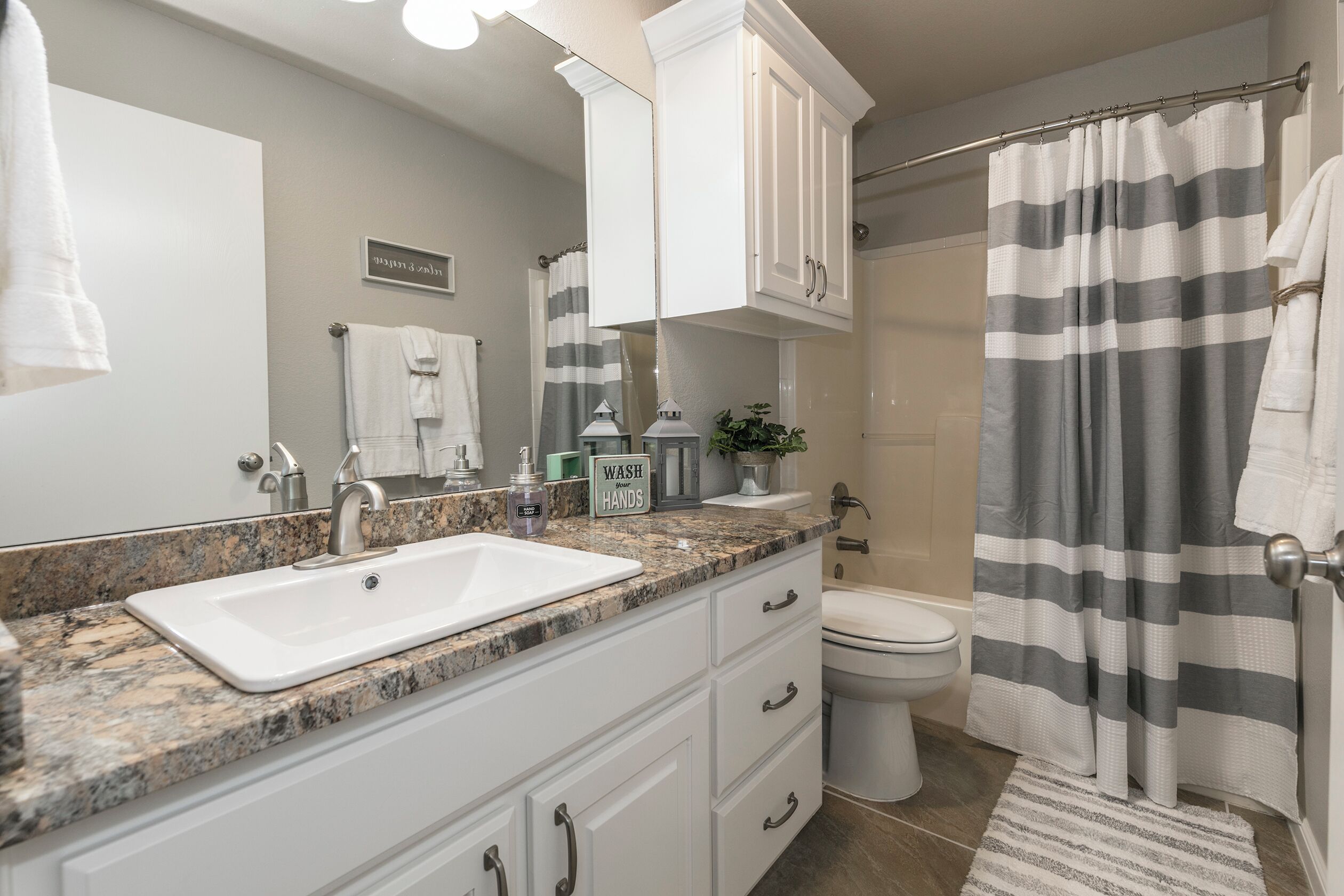 A bathroom with a white sink, vanity, and a shower curtain.