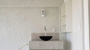 A bathroom with a freestanding sink, a towel rack, and a small mirror.