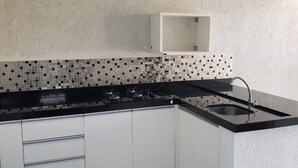 A modern kitchen with white cabinets, a black countertop, and a tiled backsplash.