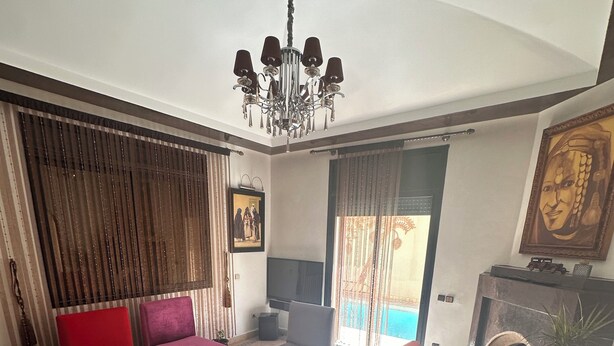 Una sala de estar con chimenea, televisor y un ventanal con cortinas.