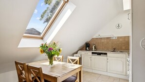 Un comedor con una mesa y sillas de madera, un jarrón de flores y vistas al cielo a través de un tragaluz.