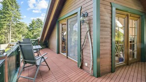 A wooden deck with a glass door and windows, a metal chair, and a ladder leaning against the wall. - Stunning home in Kenz Küstrow (Kenz Küstrow)
