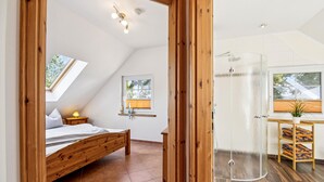 A bedroom with a wooden bed, a skylight, a glass shower, and a view of the outdoors. - Stunning home in Kenz Küstrow (Kenz Küstrow)