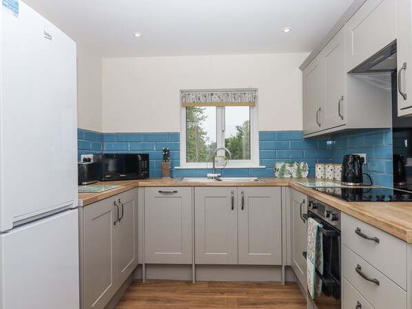 A modern kitchen with a refrigerator, microwave, sink, and stove.