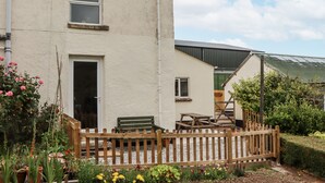 A house with a wooden deck, a bench, and a table. - Aunty Junes Cottage (Okehampton)