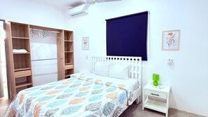 Et soveværelse med en seng, et klædeskab, et natbord og en ventilator i loftet.