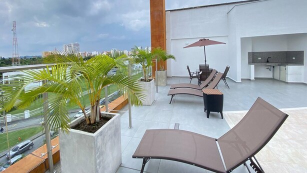 A rooftop terrace with lounge chairs, a table, and an umbrella. There are potted plants and a view of the cityscape. - Charming 1-bedroom apartment near Salento, Finlandia, and Parque Del Cafe (Armenia)