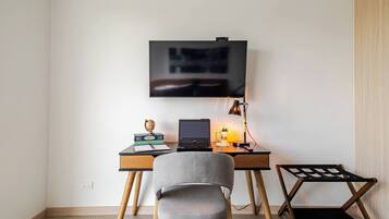 Ein moderner Arbeitsplatz mit Schreibtisch, Laptop und einem montierten Fernseher.