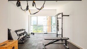 A gym with a pull-up bar, weight bench, dumbbells, and a squat rack. - Charming 1-bedroom apartment near Salento, Finlandia, and Parque Del Cafe (Armenia)
