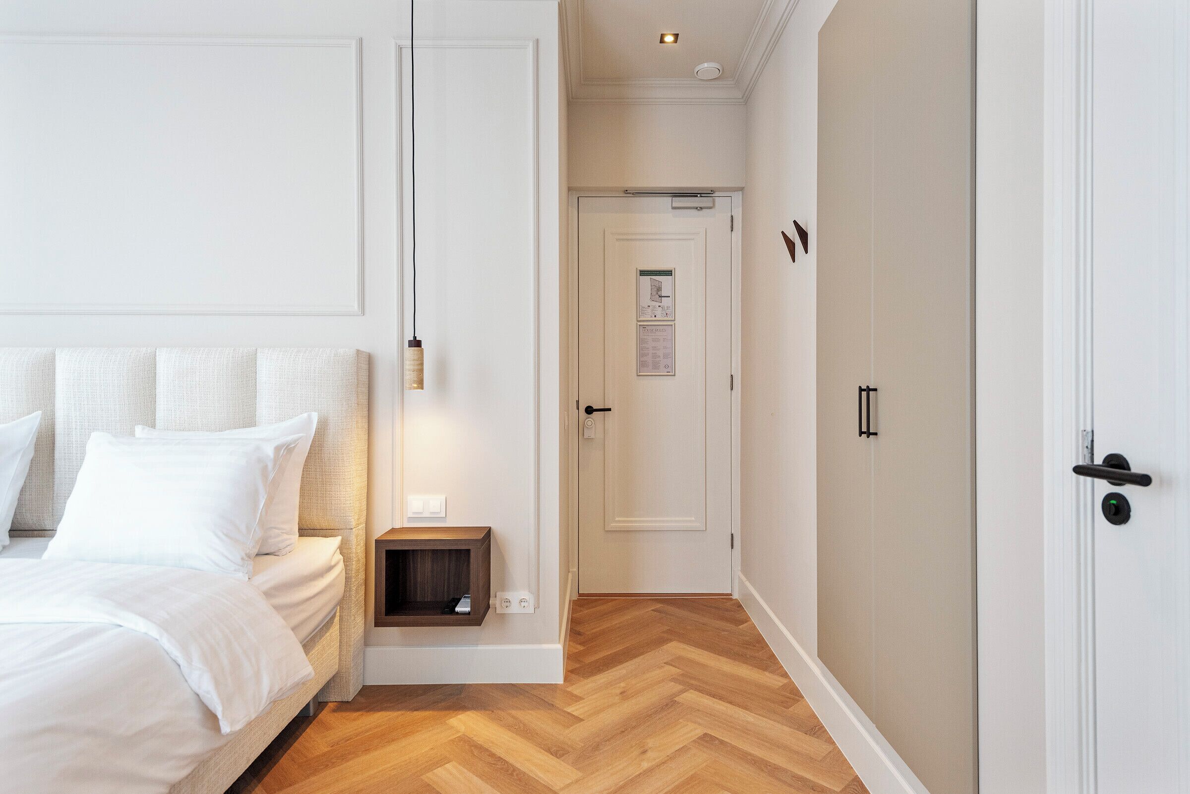 Un dormitorio con cama, mesita de noche y puerta que da a otra habitación.