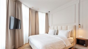 Un dormitorio moderno con una cama grande, un televisor de pantalla plana en la pared y una mesita de noche con lámpara.