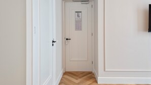 Un pasillo estrecho con una puerta blanca que tiene un mapa pequeño y un aviso.