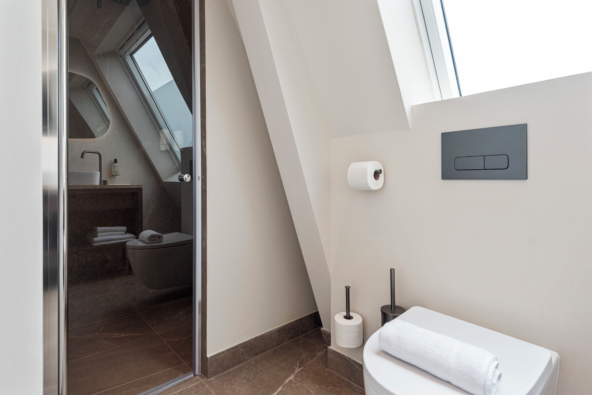 Ein modernes Badezimmer mit Duschkabine aus Glas, Toilette und Waschbecken.