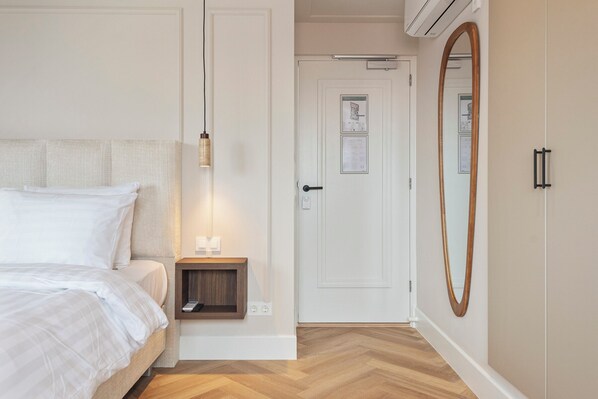 A bedroom with a bed, bedside table, and a mirror.