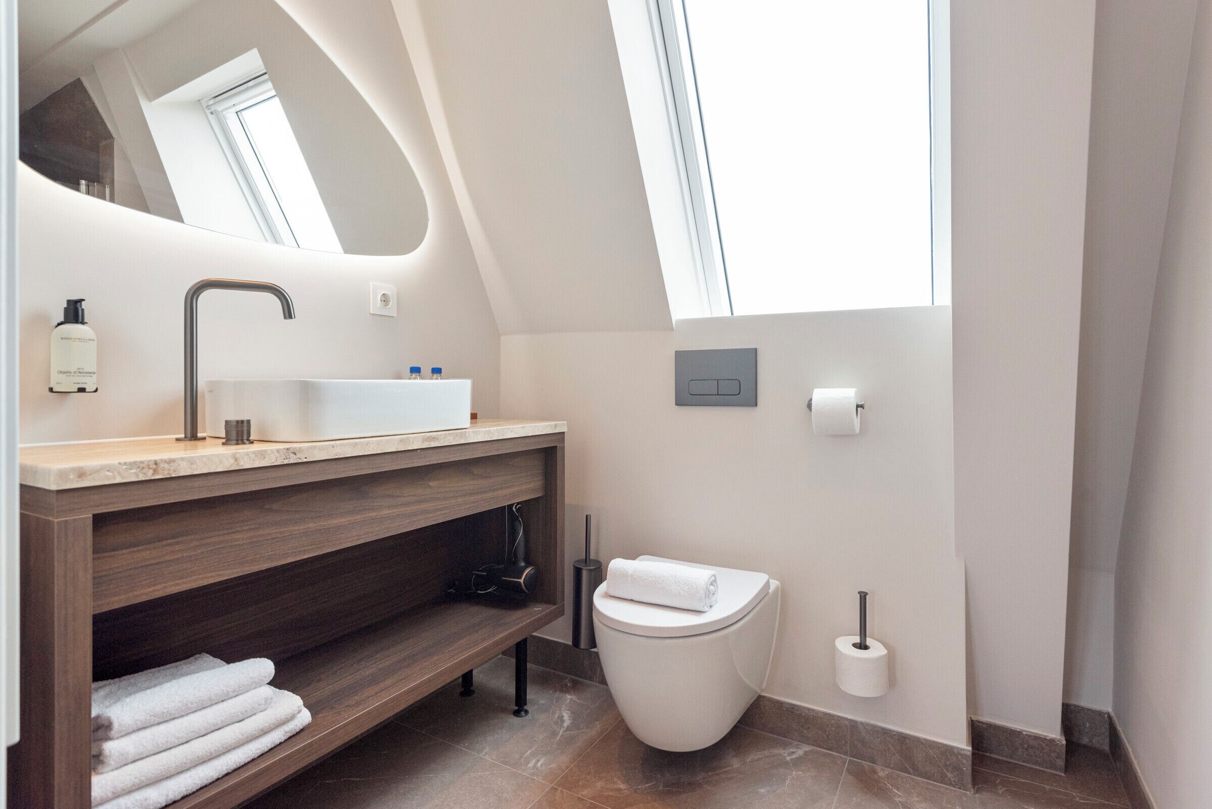 A modern bathroom with a skylight, a sink, a toilet, and a towel rack.