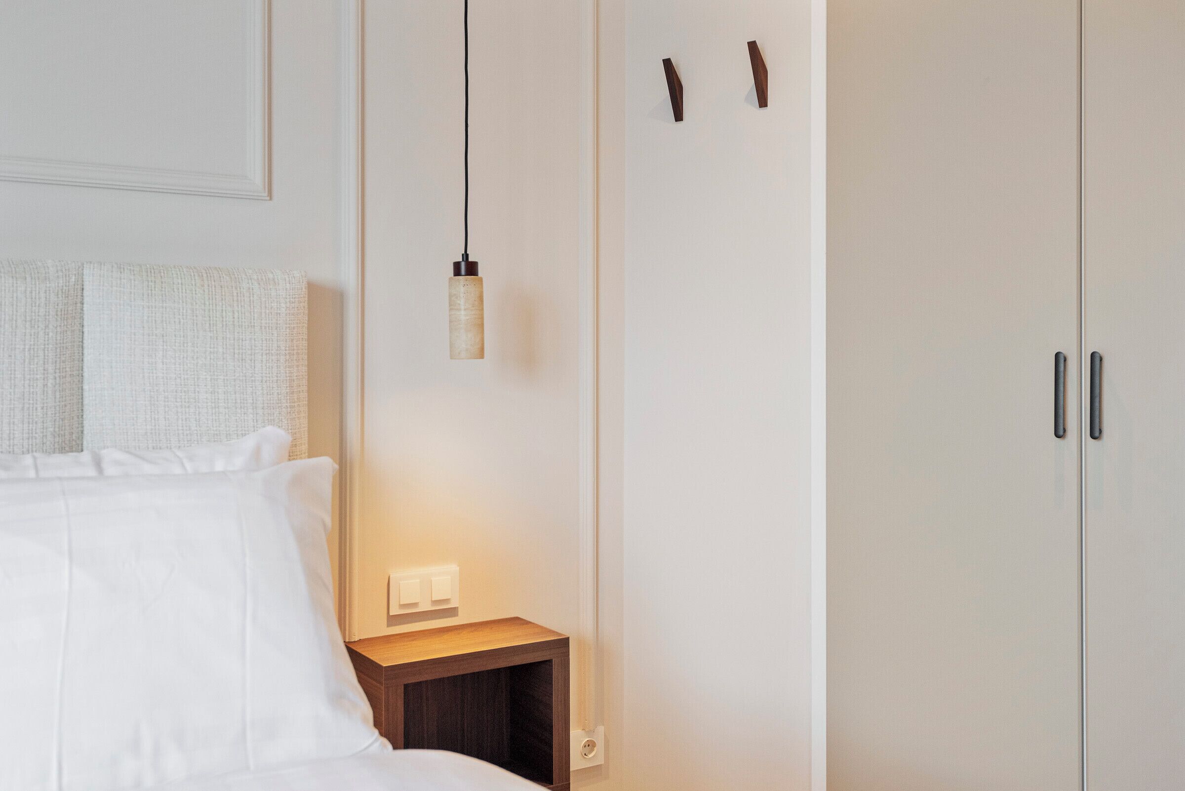 Ett sovrum med en säng, ett sängbord, en väggmonterad lampa och en garderob.