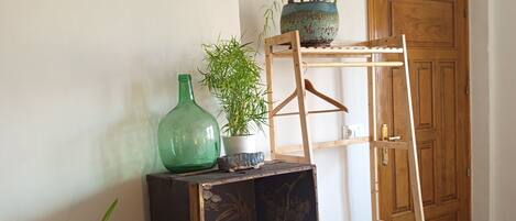 A room with a wooden ladder shelf, a small table with a vase and plant, and a patterned rug.