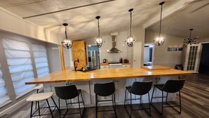 Una cocina moderna con una isla grande, taburetes negros tipo barra e iluminación colgante.