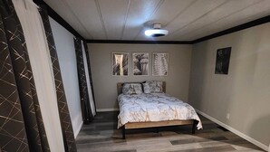 Un dormitorio con una cama, un ventilador de techo y tres cuadros colgados en la pared.