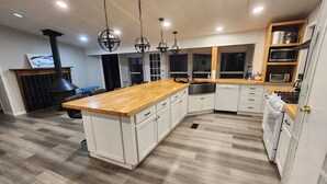 Una cocina moderna con una isla de madera, armarios blancos y un horno empotrado.