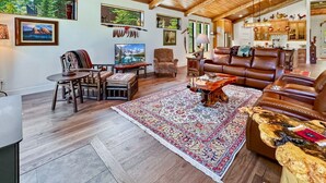 Ein geräumiges Wohnzimmer mit großem Teppich, Ledersofas, Holzmöbeln und einem Essbereich.