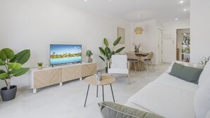 Una sala de estar moderna con un televisor de pantalla plana, un comedor y un sofá.