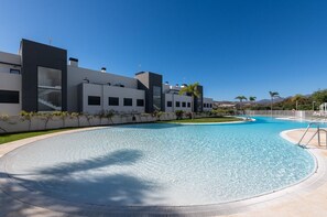 Piscina com um edifício moderno ao fundo.