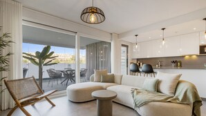 A modern living room with a sectional sofa, a round coffee table, and a wicker chair. - Luxury 3 BR apartment with terrace, pool & gym (La cala de mijas)