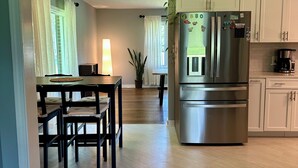 Una cocina moderna con un refrigerador de acero inoxidable, una mesa de comedor de madera y sillas.