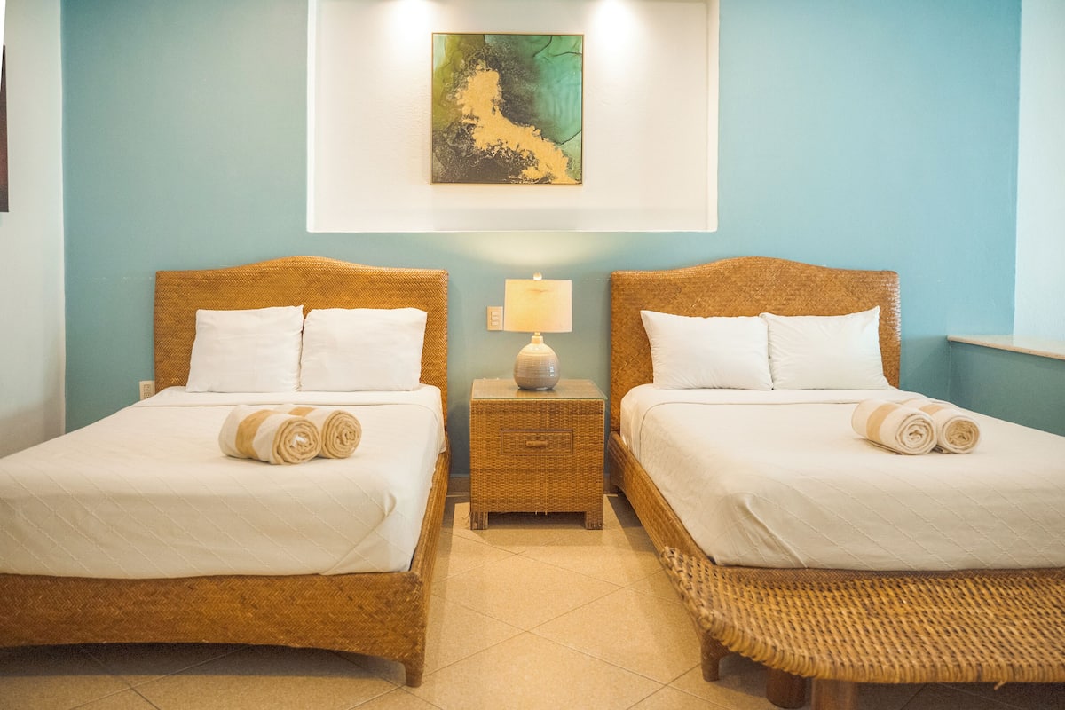 Une chambre d’hôtel avec deux lits, une table de chevet avec une lampe et un tableau au mur.