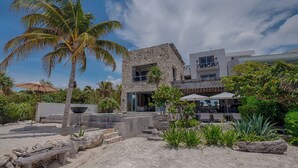 A beachfront property with a stone building, a pool area, and tropical vegetation.