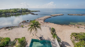 A beachfront property with a swimming pool, sandy beach, and a view of the ocean.