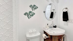 Ein Badezimmer mit Toilette, Waschbecken mit Spiegel darüber und Wandbildern von Fischen.