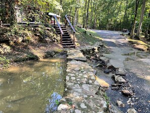 A stone bridge over a stream with a wooden staircase leading to a wooden structure. - Oak Shores Oasis on Lake Ouachita! (Mount Ida)