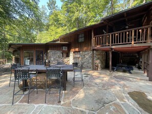 A rustic cabin with a stone patio, outdoor seating, and a covered deck area. - Oak Shores Oasis on Lake Ouachita! (Mount Ida)