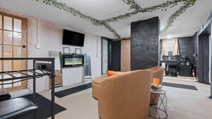 A modern living room with a sofa, a TV, and a kitchen area visible in the background.
