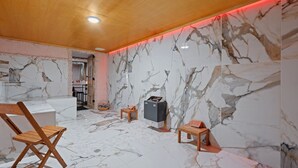 A room with marble walls and a wooden ceiling, featuring a seating area with a chair and a small table.