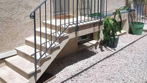 A building with a stone facade, a small porch with steps, and a metal railing. - Lovely country T2 near town center! (Aix-en-Provence)