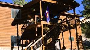 Eine Holzhütte mit Balkon, einer Flagge und einer Treppe.