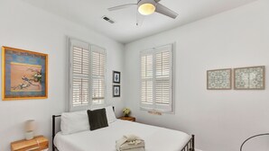 A bedroom with a bed, a nightstand, a chair, and a ceiling fan. - Retreat on Spring, Unit B (Charleston)