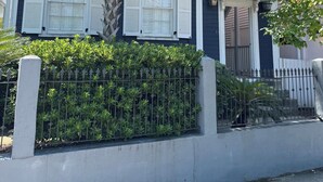 A two-story house with a balcony, white shutters, and a palm tree. - Retreat on Spring, Unit B (Charleston)