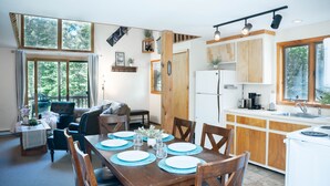 Een moderne keuken met houten kastjes, een witte koelkast en een eethoek met een houten tafel gedekt voor vier personen.