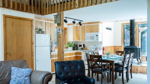 Een moderne keuken met houten kastjes, een eethoek met een tafel en stoelen, en een gezellige zithoek met een bank en een open haard.