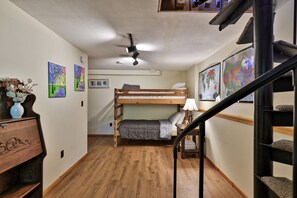A room with a bunk bed, wooden flooring, a desk with a vase, and wall art. - Bob's Sled Lodge – 2BR Killington Retreat Near Slopes & Trails (Killington)