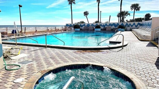 Una piscina con hidromasaje, rodeada de palmeras y vista al océano.
